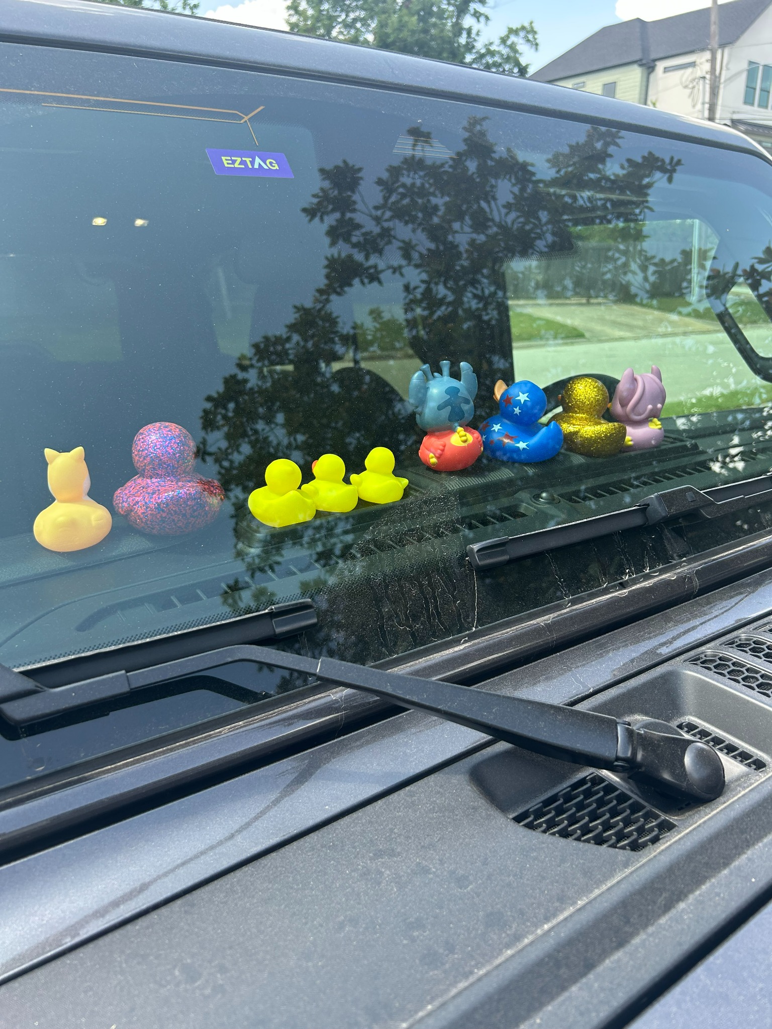 A row of dashboard ducks in a green Jeep positioned to face inward toward the passengers
